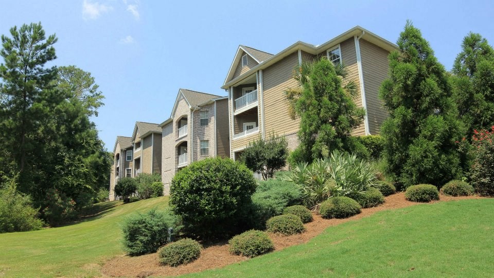 an apartment complex with a green lawn and trees