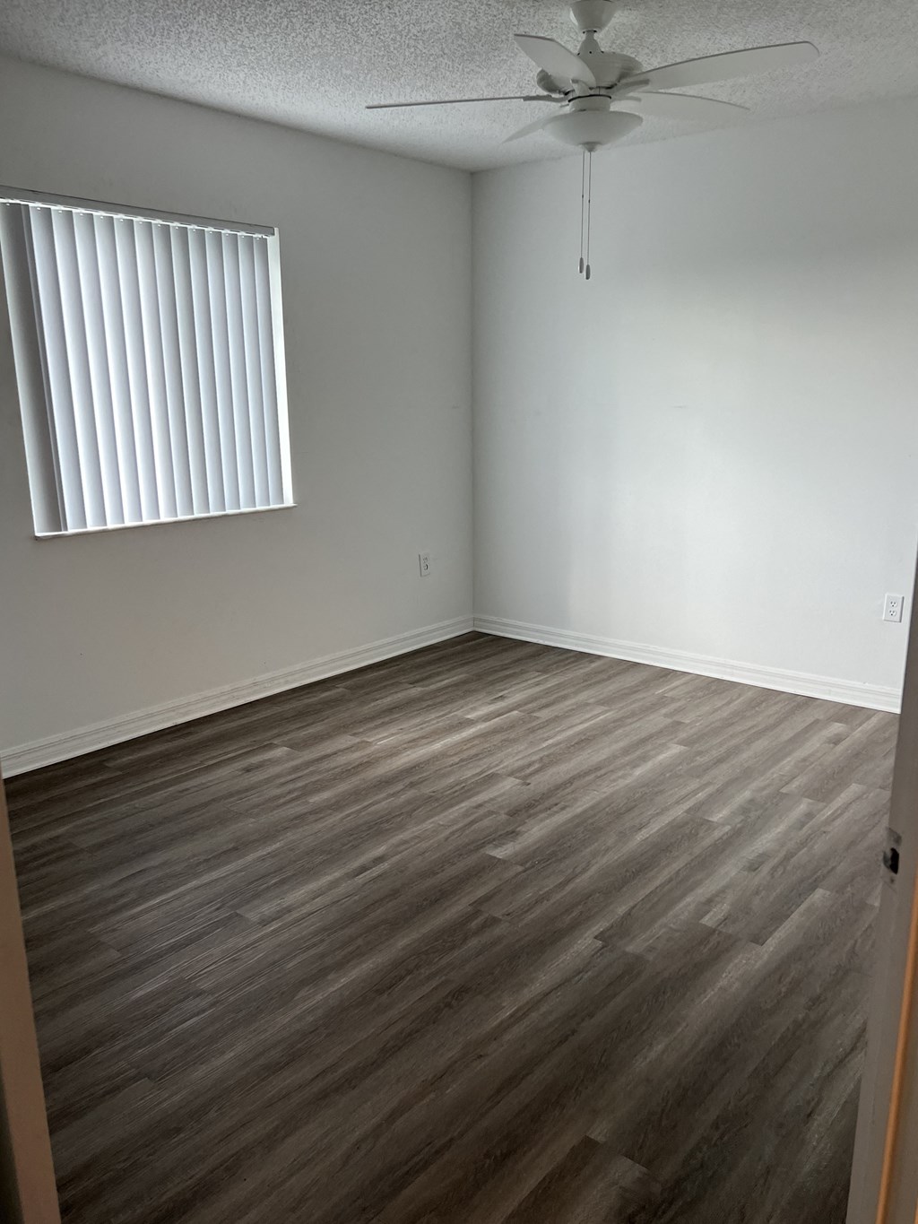 an empty room with wooden floors and a window