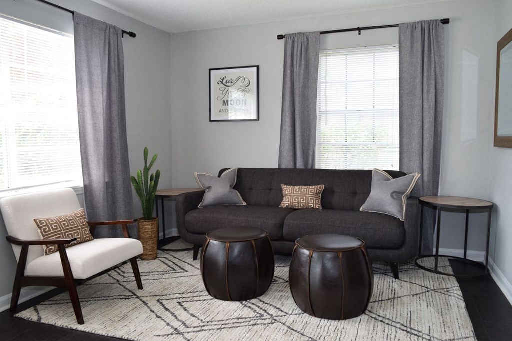 a living room with grey curtains and a black couch