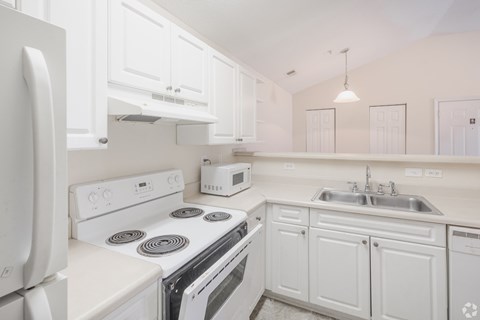 A white kitchen with a stove, oven, microwave, and sink.