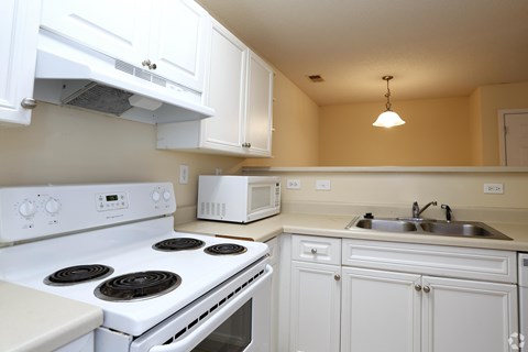 A white stove and oven in a kitchen with white cabinets.