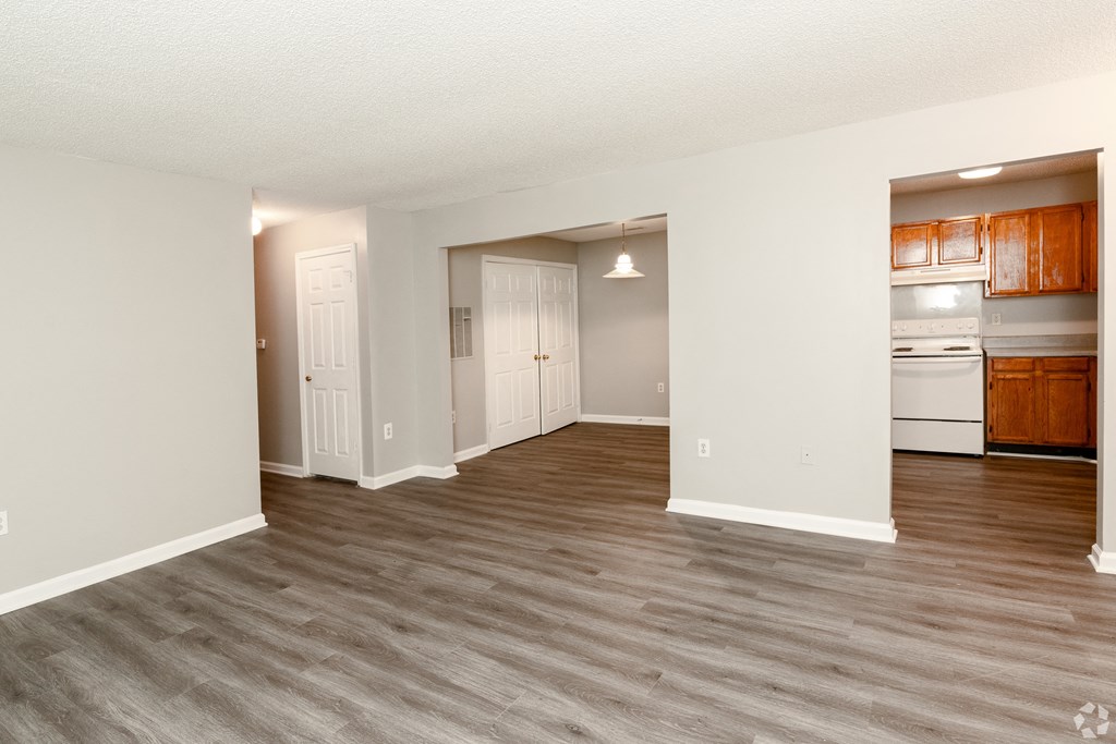 an empty living room and kitchen with white appliances and wood flooring at Avon Crossings, Durham, 27713