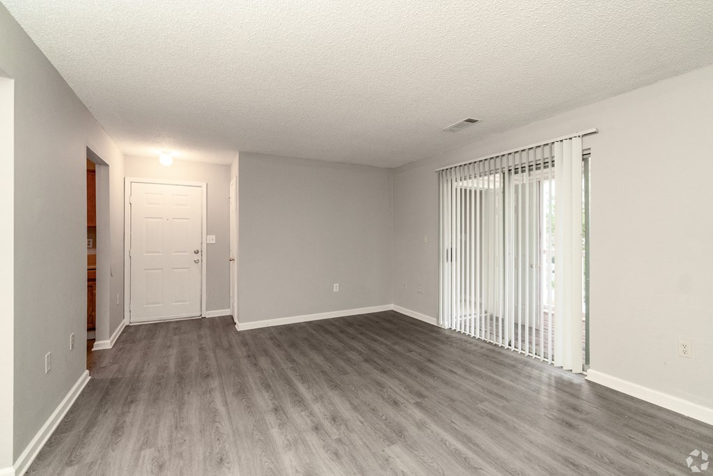 an empty living room with wood flooring and sliding glass doors at Avon Crossings, Durham, NC 27713