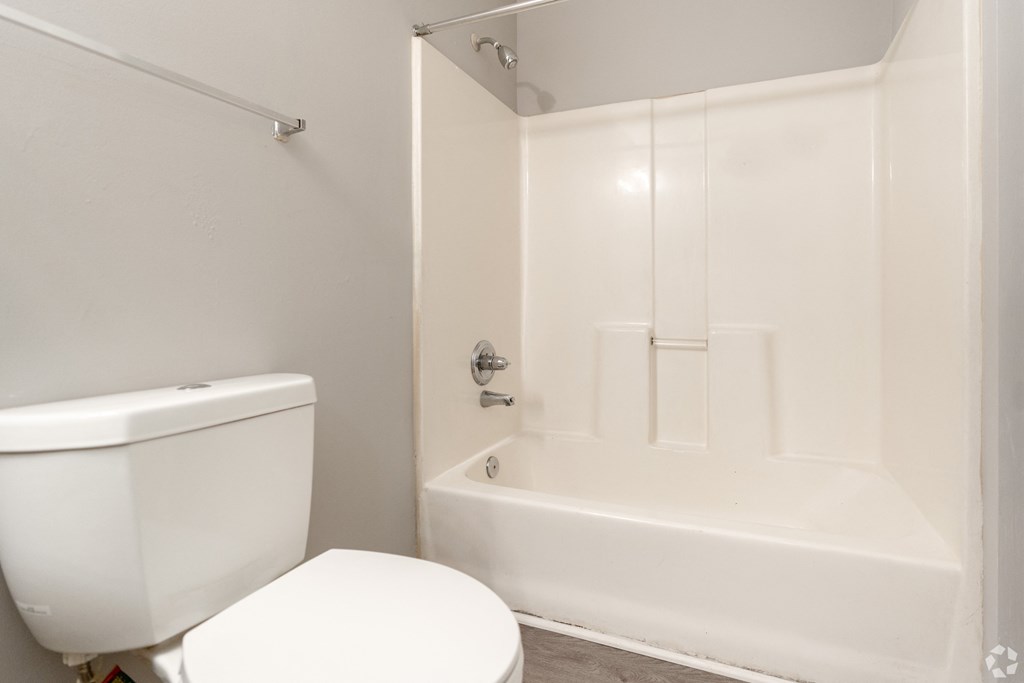 a white bathroom with a toilet and a tub at Avon Crossings, Durham