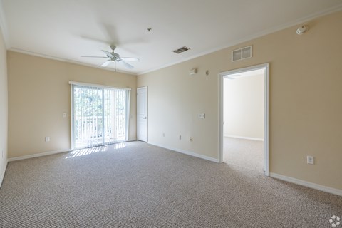 A spacious room with a ceiling fan and carpeted floor.