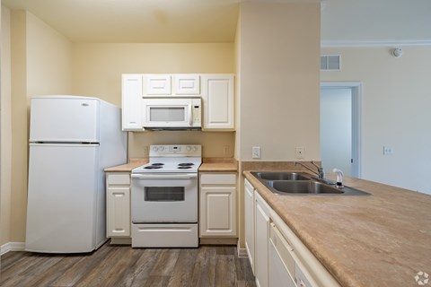 A kitchen with a white refrigerator, stove, and microwave.
