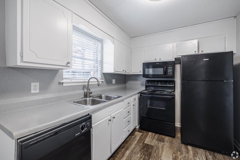 A kitchen with black appliances and white cabinets.at Brandywine Townhomes, Goose Creek, SC