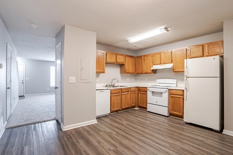 A kitchen with white appliances and wooden cabinets.