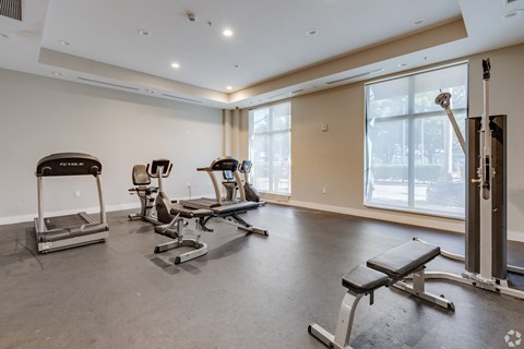 A spacious gym with treadmills, exercise bikes, and a bench press.