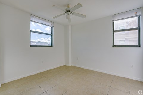A room with a ceiling fan and two windows.