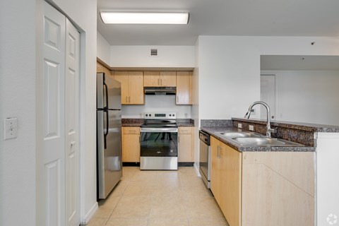 A kitchen with a refrigerator, oven, and sink.