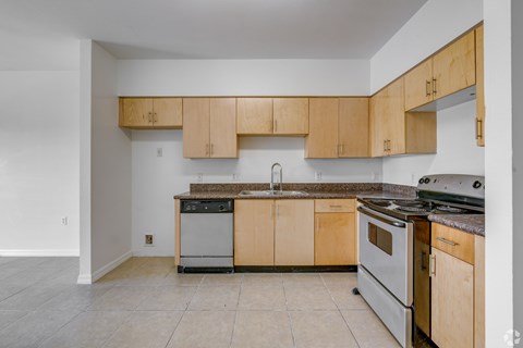 A kitchen with wooden cabinets and a stainless steel dishwasher.
