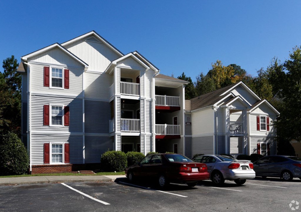 an apartment building with cars parked in a parking lot at Avon Crossings, North Carolina