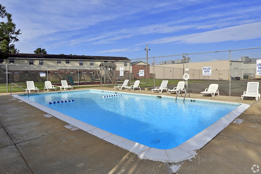 A large blue swimming pool with white lounge chairs around it.at Brandywine Townhomes, Goose Creek, SC  