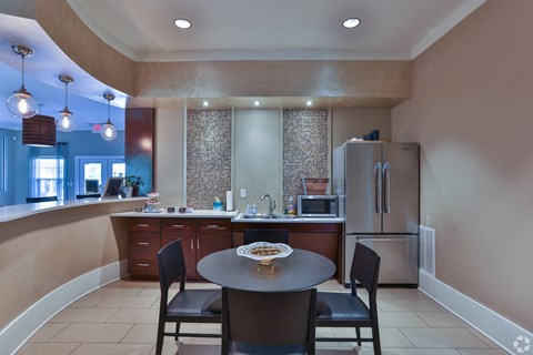 A kitchen with a table and chairs in the foreground and a refrigerator in the background.