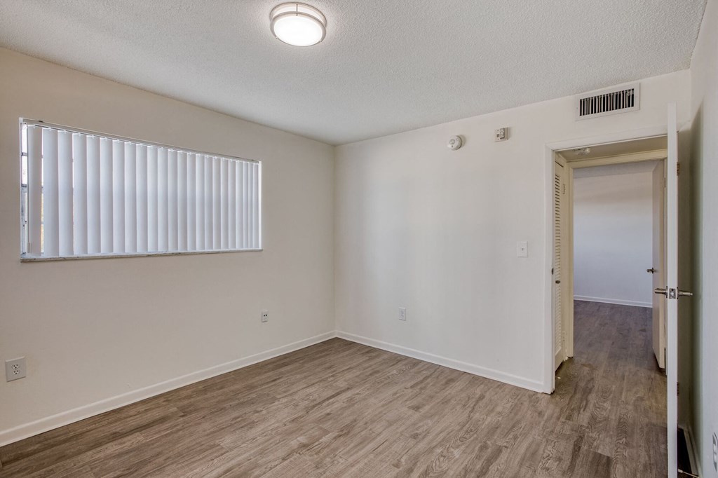 a bedroom with hardwood floors and white walls