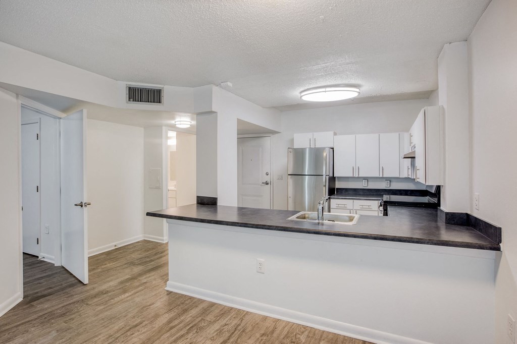 a kitchen with a large island and a stainless steel refrigerator