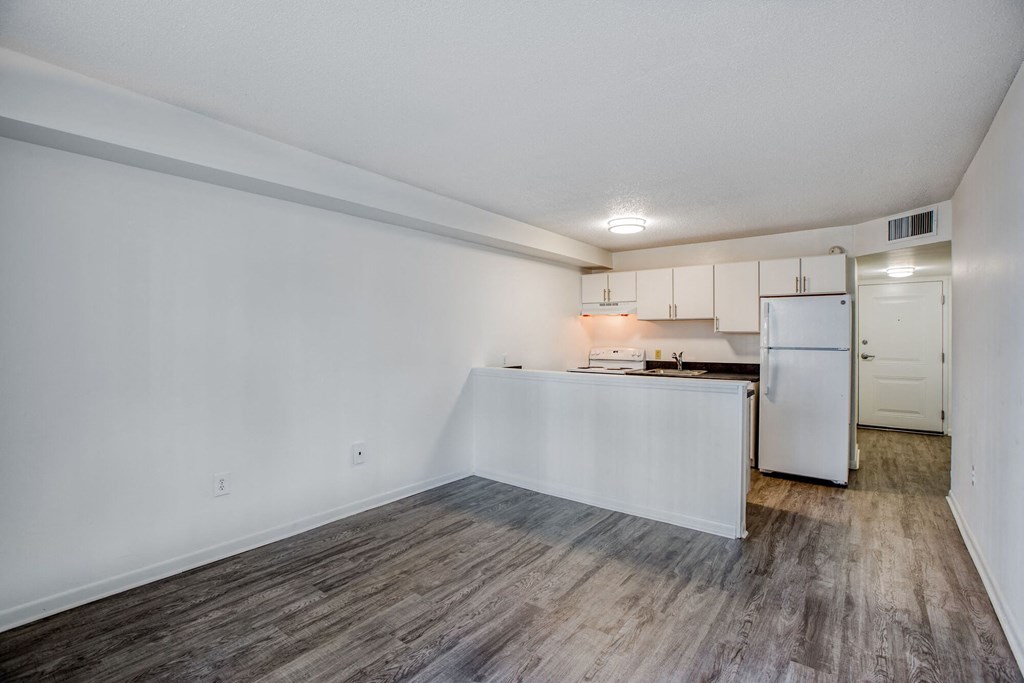a kitchen and living room with white walls and wood flooring