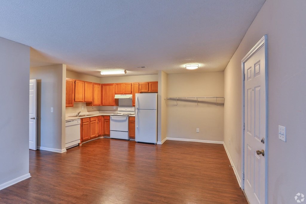 an empty kitchen with wood flooring and white appliances