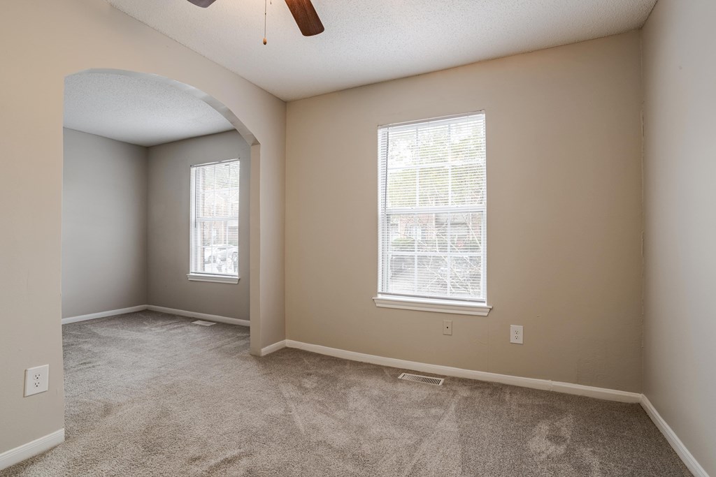 A room with a carpeted floor and a window with blinds.