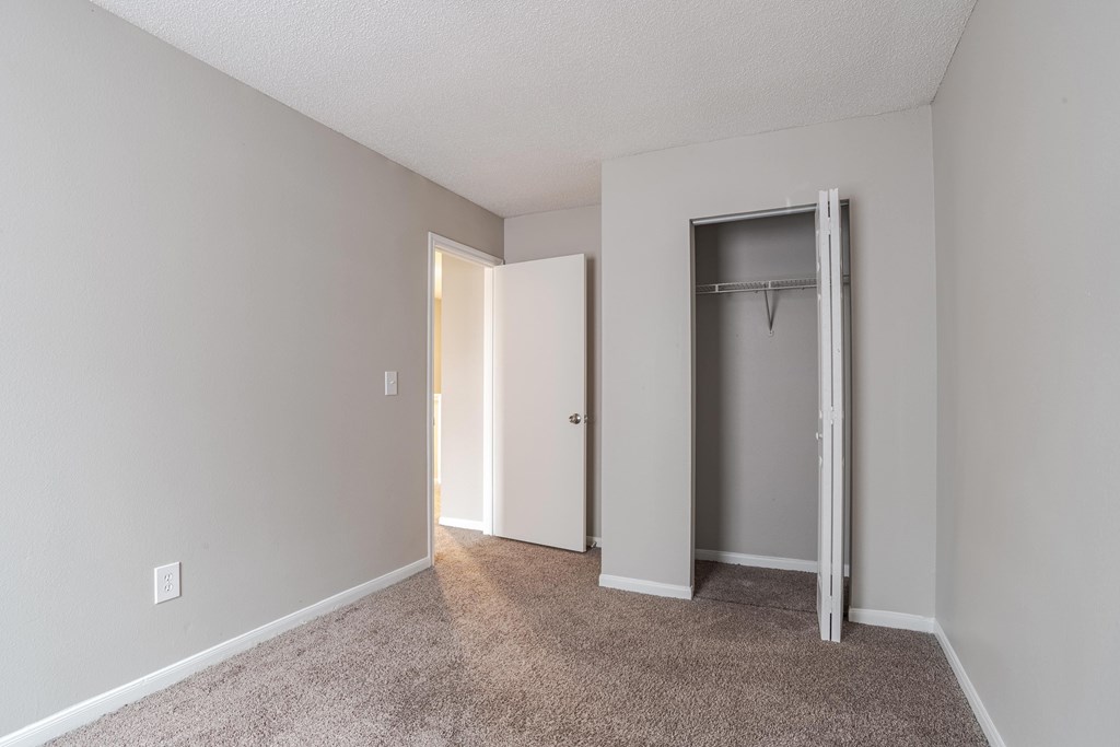 A room with a carpeted floor and two doors, one of which is open.