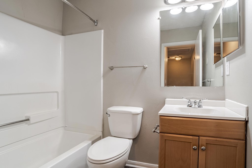A white bathroom with a toilet, sink, and mirror.