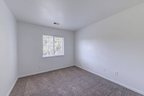a bedroom with white walls and a window at Carolina Springs Apartments, Carrboro, NC 27510