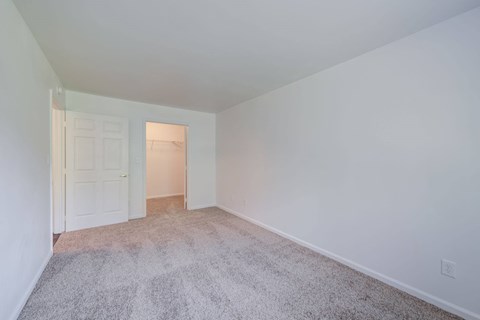 a bedroom with a carpeted floor and a door to a closet at Carolina Springs Apartments, Carrboro, NC