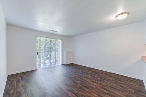 an empty living room with wood flooring and a sliding glass door at Carolina Springs Apartments, Carrboro, North Carolina
