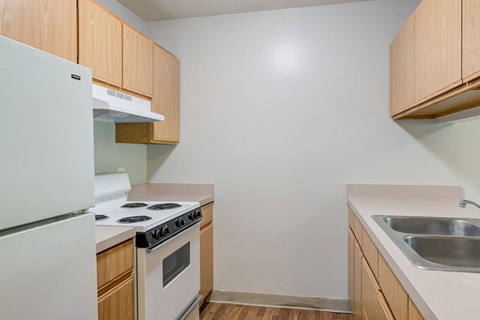 A kitchen with a white refrigerator, white stove, and wooden cabinets.