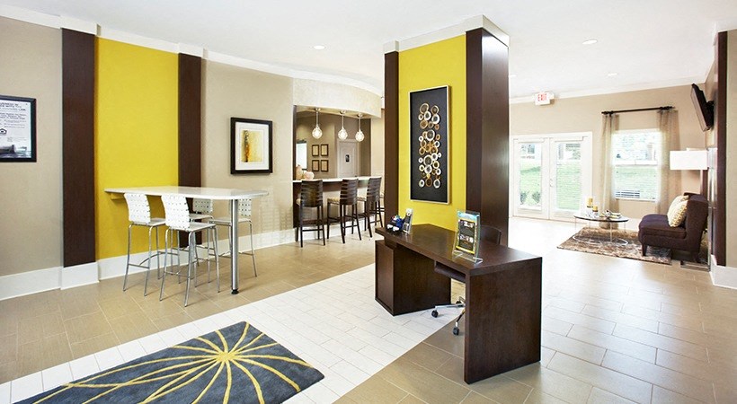 a room with a desk and chairs in it and a kitchen in the background