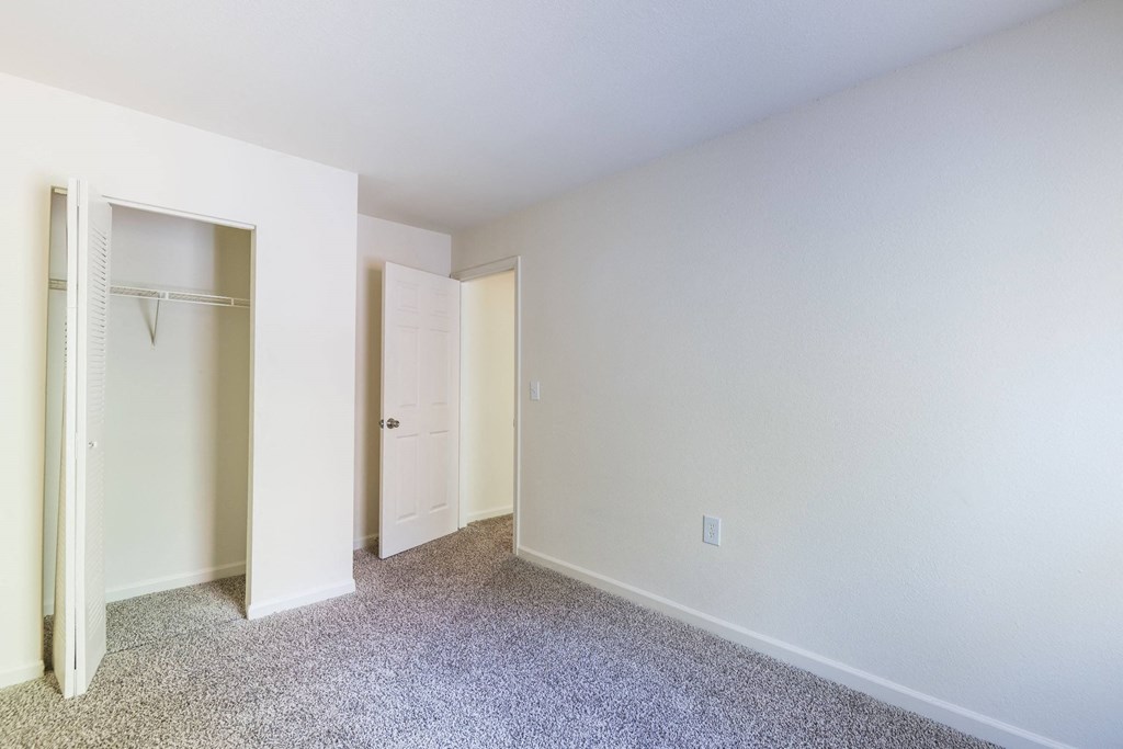 a bedroom with white walls and carpet and a closet at Crescent Pointe, Stafford, VA