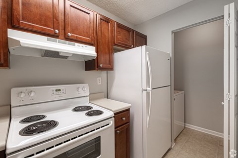 A white stove and refrigerator in a kitchen with wooden cabinets.