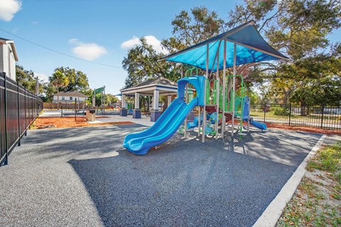 A playground with a blue slide and a blue canopy.