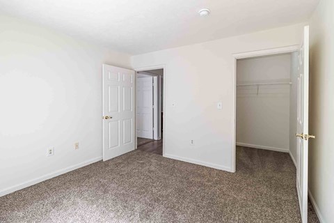 A room with a carpeted floor and two doors, one of which is open.