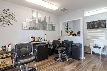 A room with a black and white theme, featuring a black chair, a black cabinet, and a black counter with a few items on it.