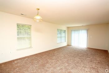 A room with a carpeted floor and a window with blinds.