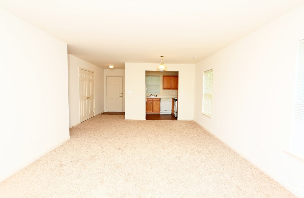 A spacious room with a kitchen area in the background. A spacious room with a kitchen area in the background at English Oaks Apartments, Virginia, 22406