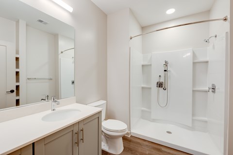 A white bathroom with a toilet, sink, and shower.
