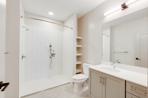A white bathroom with a toilet, sink, and shower.