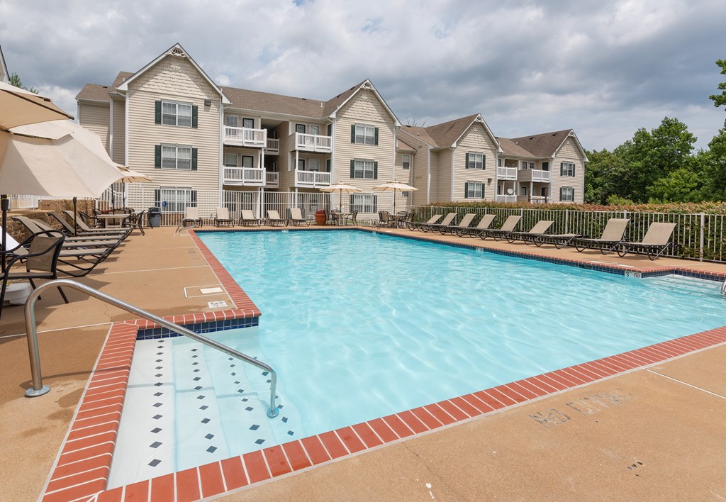 A swimming pool with a red brick border and a building in the background.at Summerland Heights, Woodbridge, 22191  