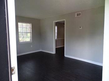 Room with dark hardwood flooring and light gray walls, lit by natural light