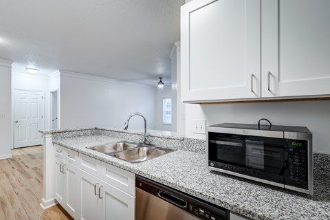A kitchen with white cabinets and a granite countertop.