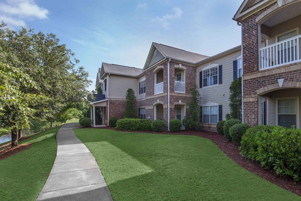 a walkway in front of an apartment building with green grass at Carrington Place at Wildewood, Columbia  