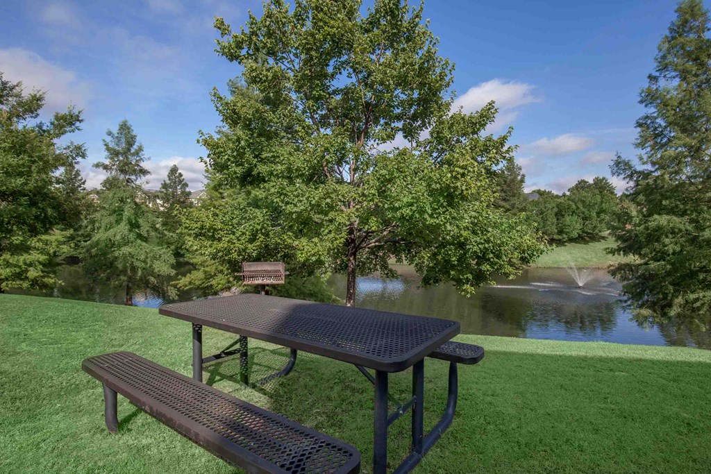 a picnic table with benches next to a body of water at Carrington Place at Wildewood, Columbia, 29223  