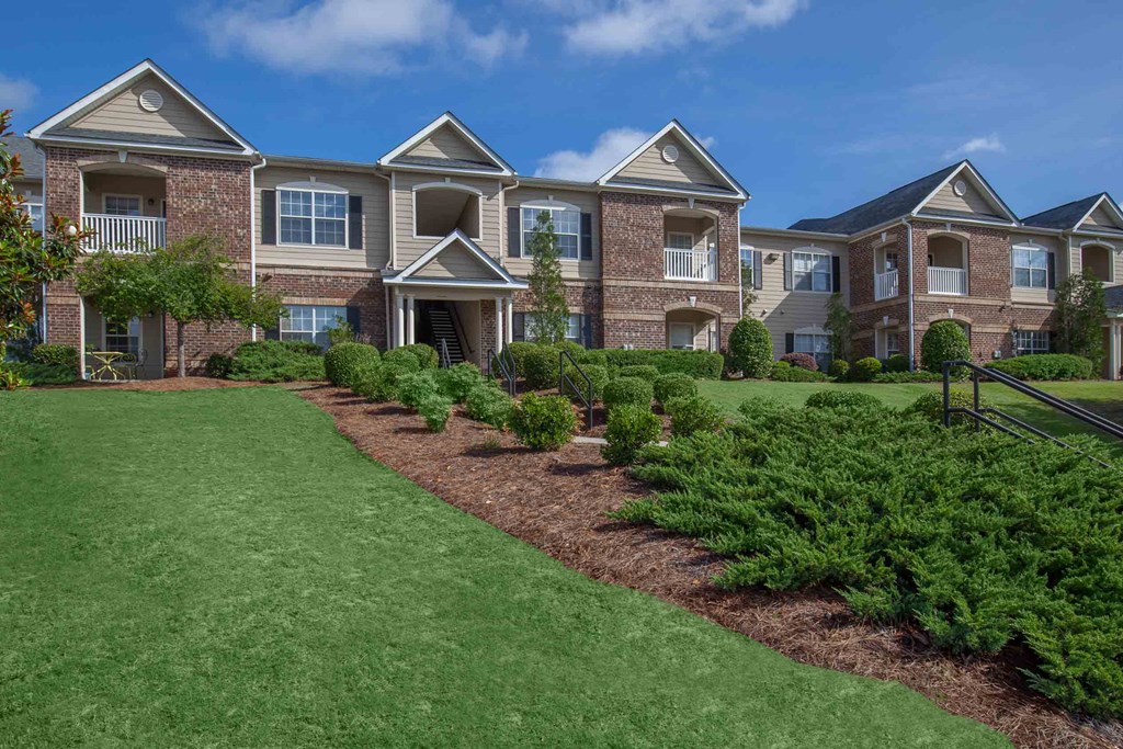 an exterior view of an apartment building with green grass and shrubs