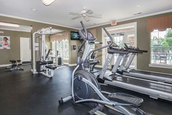 A gym with a treadmill, elliptical machines, and other exercise equipment.