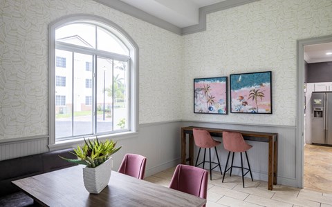 a dining room with two paintings on the wall and a wooden table with pink chairs
