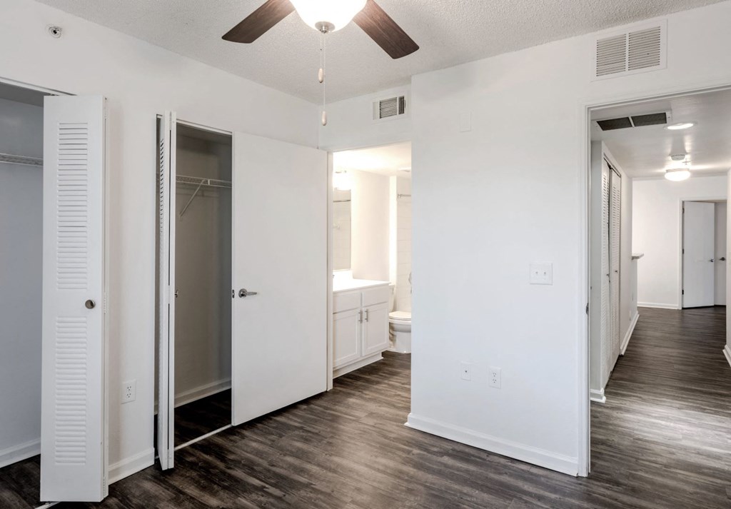 a bedroom with white walls and a ceiling fan