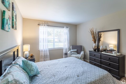 A bedroom with a large bed and a mirror on the dresser.at Bradley Square, North Charleston, 29406  